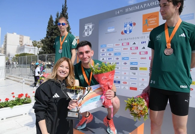 Η Νάνση Βέρρα, Chief Legal, Regulatory & Compliance Officer της Allwyn Hellas, βραβεύει τον Ορφέα Ιωάννου, που αναδείχθηκε νικητής στους άνδρες στον Αγώνα Δρόμου των 5 χλμ. Allwyn